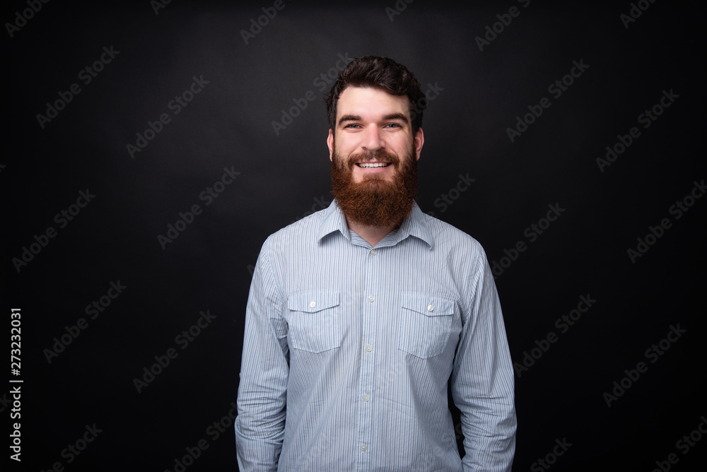 Portrait of handsome bearded man wearing shirt over dark isolated background