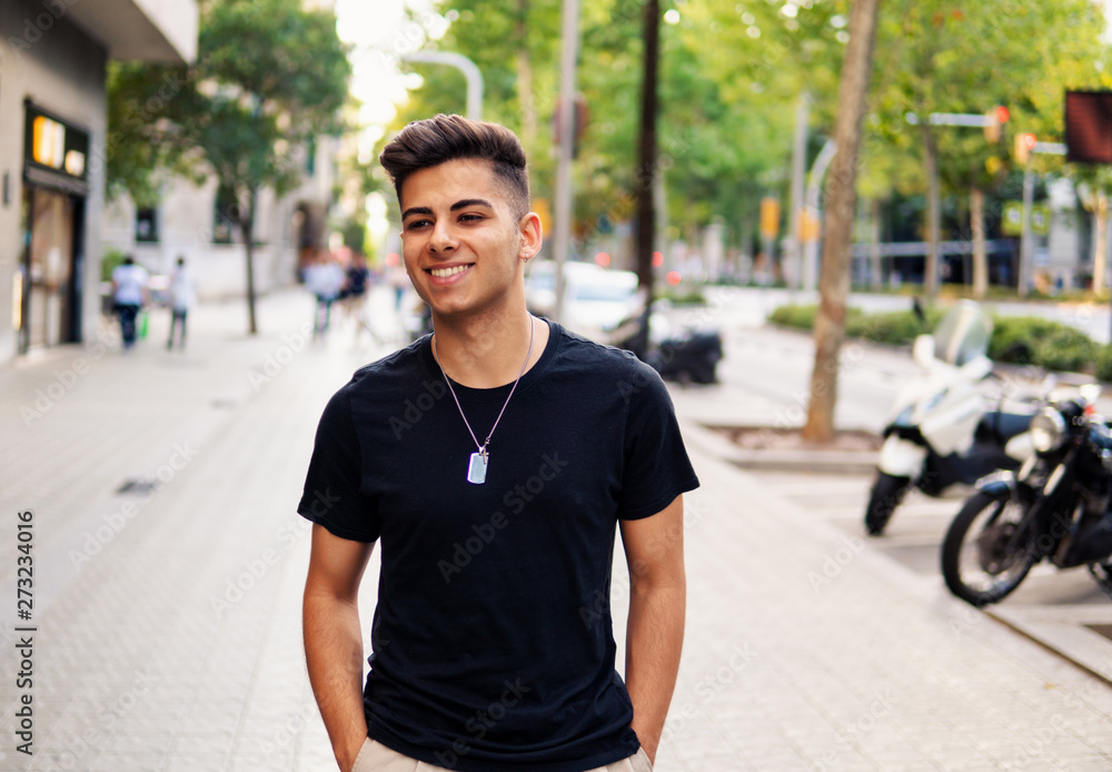 Young fashionable handsome man on the street of modern city. He looks happy