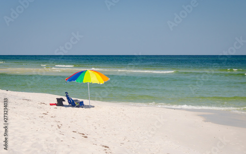 Umbrella and chairs set up at beach shoreline. Beautiful tropical Gulf Coast ocean beach white sands and sea. Vacation tourist travel destination for fun and relaxation.