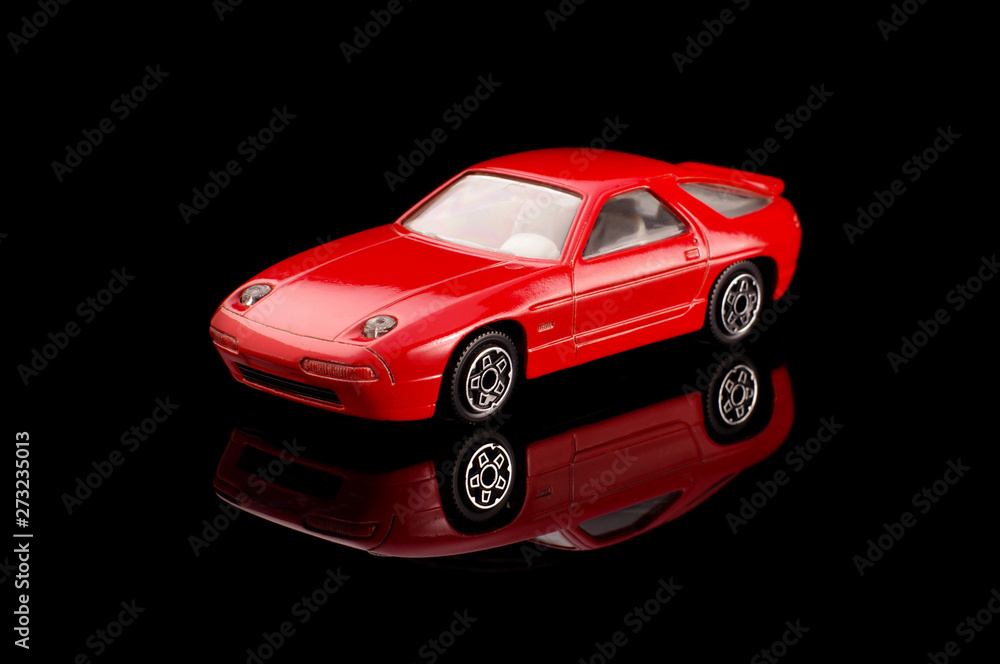 Red modern die-cast model car on the black reflective background