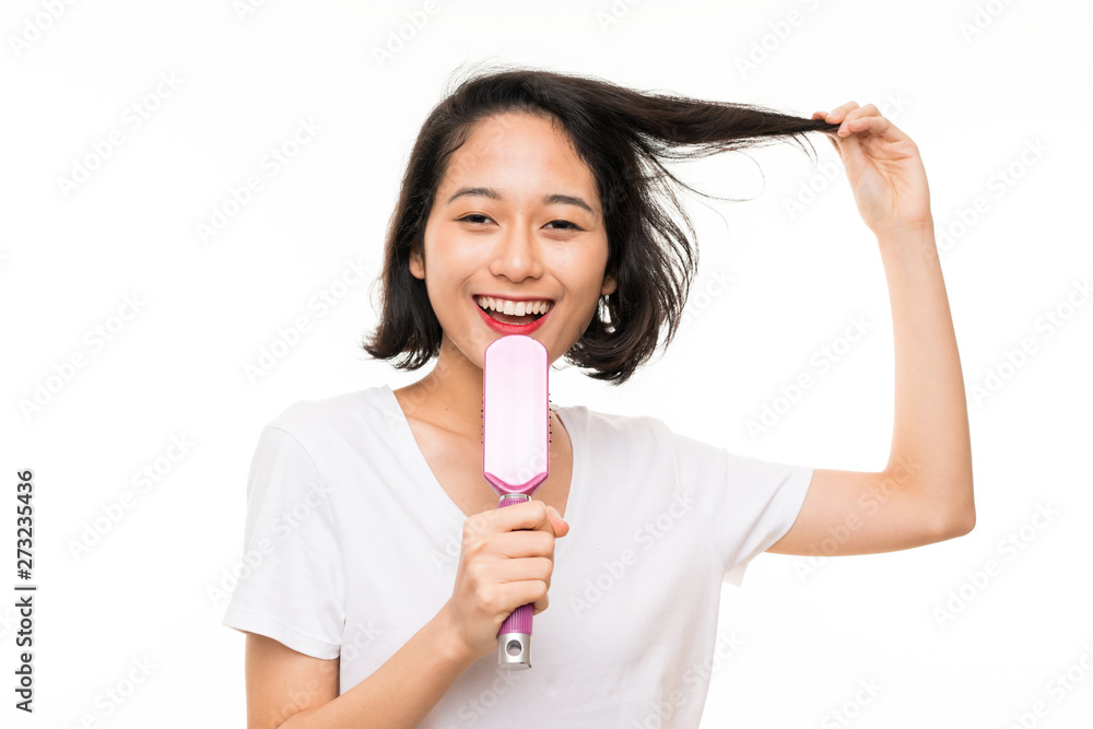 Asian young woman over isolated background with hair comb
