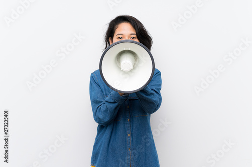Asian young woman over isolated white background shouting through a megaphone