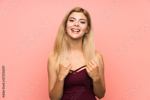 Teenager girl over isolated pink background celebrating a victory