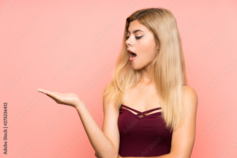 Teenager girl over isolated pink background holding copyspace imaginary on the palm Teenager girl over isolated pink background holding copyspace imaginary on the palm