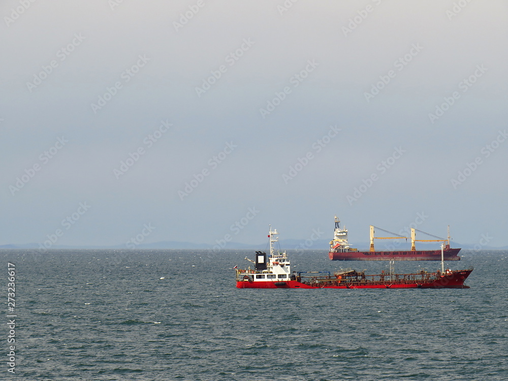 Two cargo ships at anchor on the sky and sea background with empty space for your text
