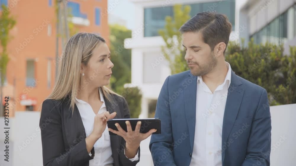 Smiling young business people using tablet pc. Young businessman and businesswoman using digital tablet together outdoor. Technology concept Smiling young business people using tablet pc. Young businessman and businesswoman using digital tablet together outdoor. Technology concept