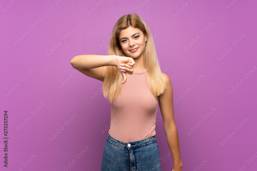 Teenager girl over isolated purple background showing thumb down with negative expression Teenager girl over isolated purple background showing thumb down with negative expression