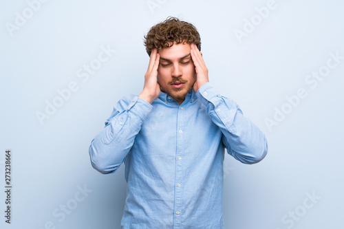 Blonde man over blue wall with headache
