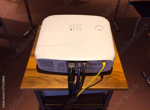 White screen projector  on a wooden stance in a dark conference or lecture hall