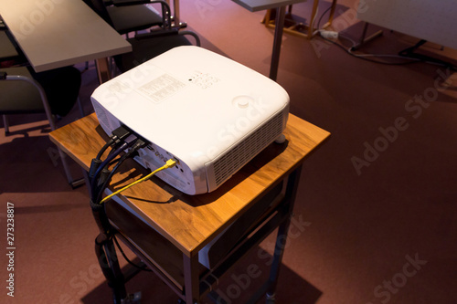 White screen projector  on a wooden stance in a dark conference or lecture hall