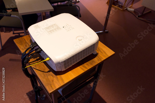 White screen projector  on a wooden stance in a dark conference or lecture hall