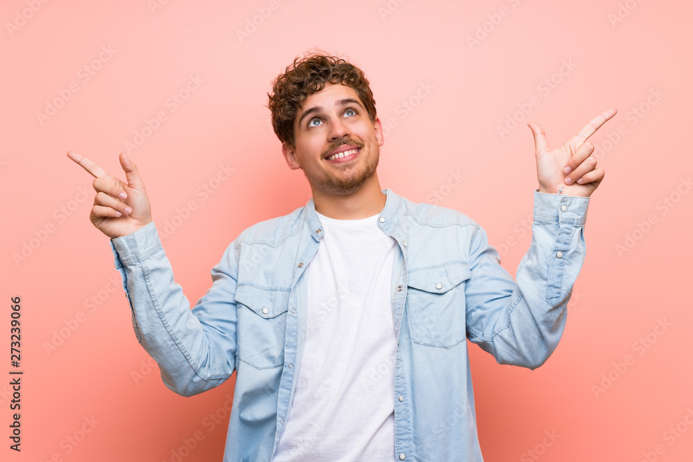 Blonde man over pink wall pointing with the index finger a great idea Blonde man over pink wall pointing with the index finger a great idea