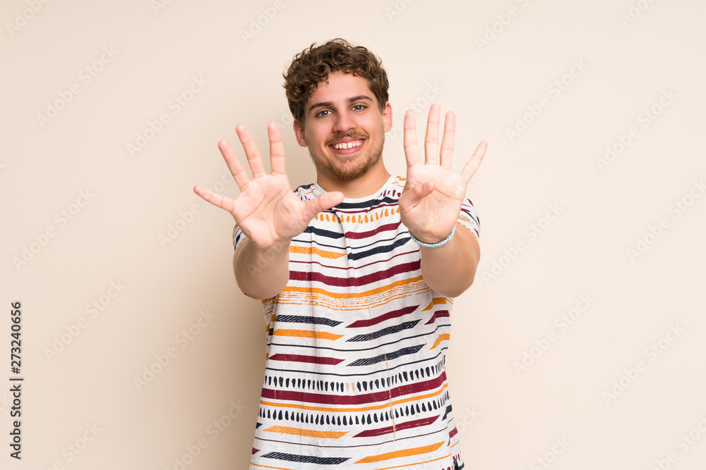 Blonde man over isolated wall counting nine with fingers Blonde man over isolated wall counting nine with fingers