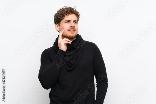 Blonde man over isolated white wall thinking an idea while looking up