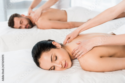 selective focus of masseur doing massage to woman with closed eyes near man in spa center