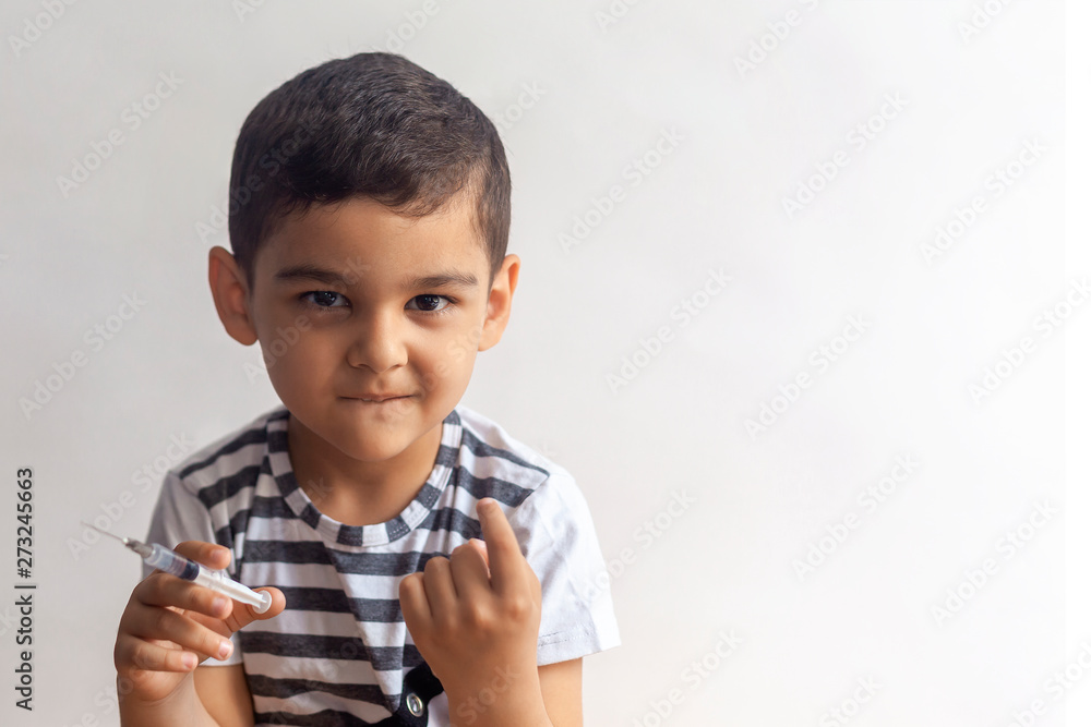 A little bad boy holding syringe and calling somone with his finger. A kid having fun at hospital A little bad boy holding syringe and calling somone with his finger. A kid having fun at hospital