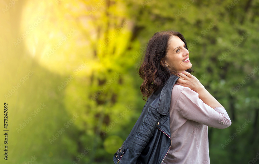 Middle-age woman in smiling, holds her jacket over the shoulder Middle-age woman in smiling, holds her jacket over the shoulder