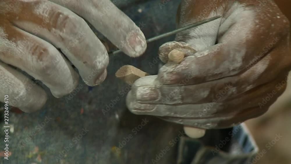 A still medium shot of a person carving out an ankle from a humanlike figure made from dough with the camera focusimg on the person's hands. A still medium shot of a person carving out an ankle from a humanlike figure made from dough with the camera focusimg on the person's hands.