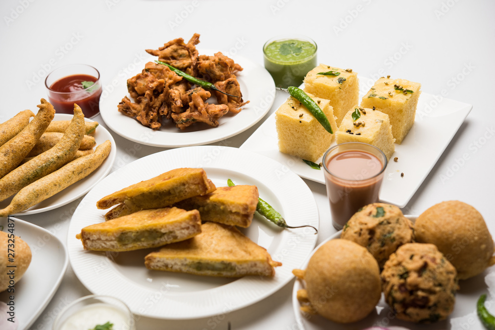 Indian Tea time snacks in group includes Veg Samosa, Kachori/kachaudi, aloo bonda, khaman dhokla, bread, onion,chilli and moong pakora/pakoda/bhaji/bhajji/Bhajiya/bajji with sauces, selective focus Indian Tea time snacks in group includes Veg Samosa, Kachori/kachaudi, aloo bonda, khaman dhokla, bread, onion,chilli and moong pakora/pakoda/bhaji/bhajji/Bhajiya/bajji with sauces, selective focus