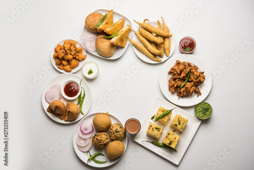 Indian Tea time snacks in group includes Veg Samosa, Kachori/kachaudi, aloo bonda, khaman dhokla, bread, onion,chilli and moong pakora/pakoda/bhaji/bhajji/Bhajiya/bajji with sauces, selective focus