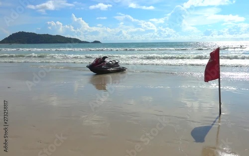 Jet ski is parking on the beach with the red flag says 