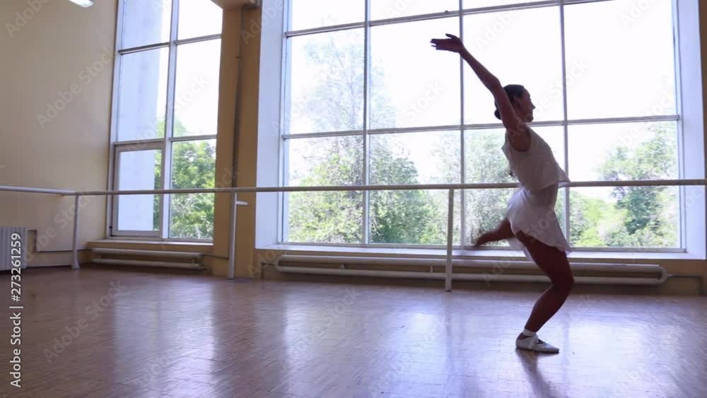 Young thin ballerina in white dress dancing near a big window. Young thin ballerina in white dress dancing near a big window.