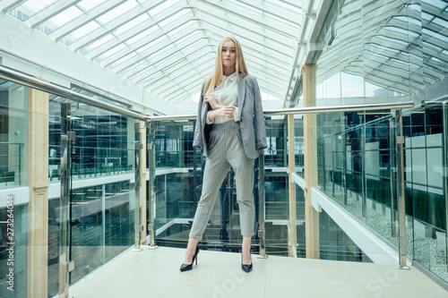Young elegant business woman in a stylish gray suit pants and jacket in a modern office with panoramic windows shopping center