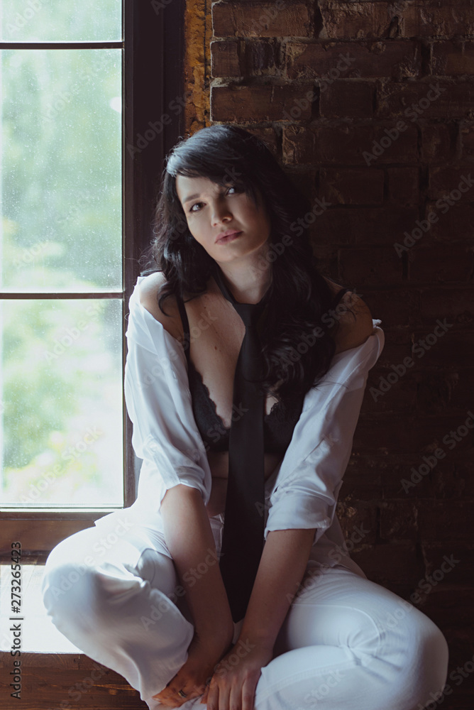 Fototapeta premium portrait of stylish, beautiful brunette woman with long hair in black bra and tie in white shirt and white pens