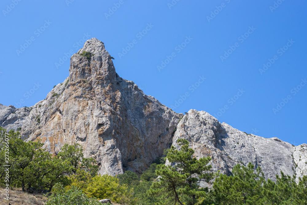 Crimean mountain peaks among green bushes against the blue sky Crimean mountain peaks among green bushes against the blue sky