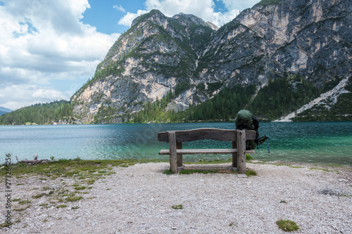 Lake Braies with vivid colors in spring with mountains in the background in the north of Italy. A backpack placed on the bench facing the lake expresses the concept of travel