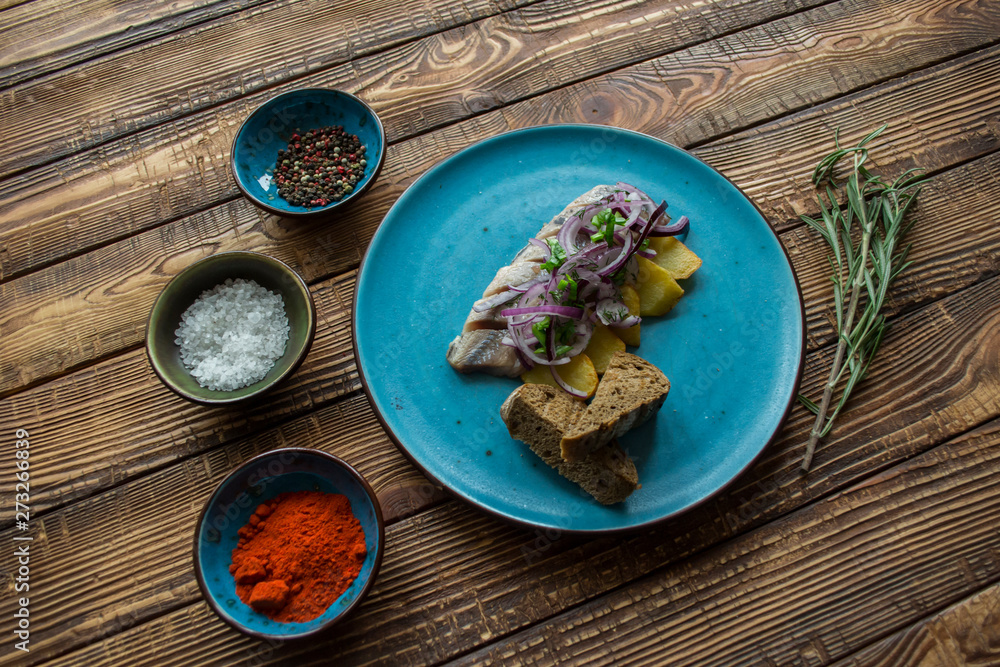 Fried potatoes and herring fish with onion on a wooden table. Fried potatoes and herring fish with onion on a wooden table.