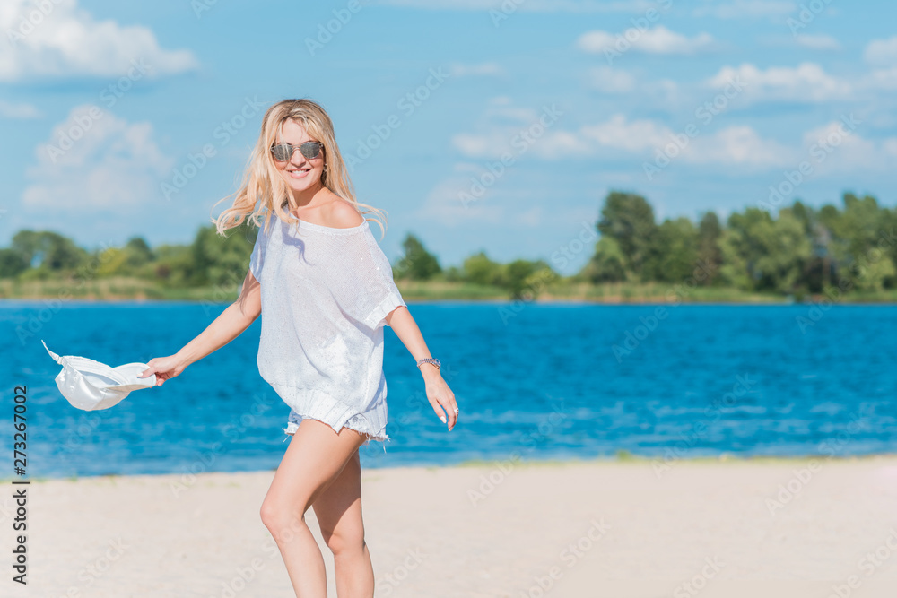 Beautiful nice blonde girl wear white tunic, shorts and baseball cap at the beach, summer fashionable concept Beautiful nice blonde girl wear white tunic, shorts and baseball cap at the beach, summer fashionable concept