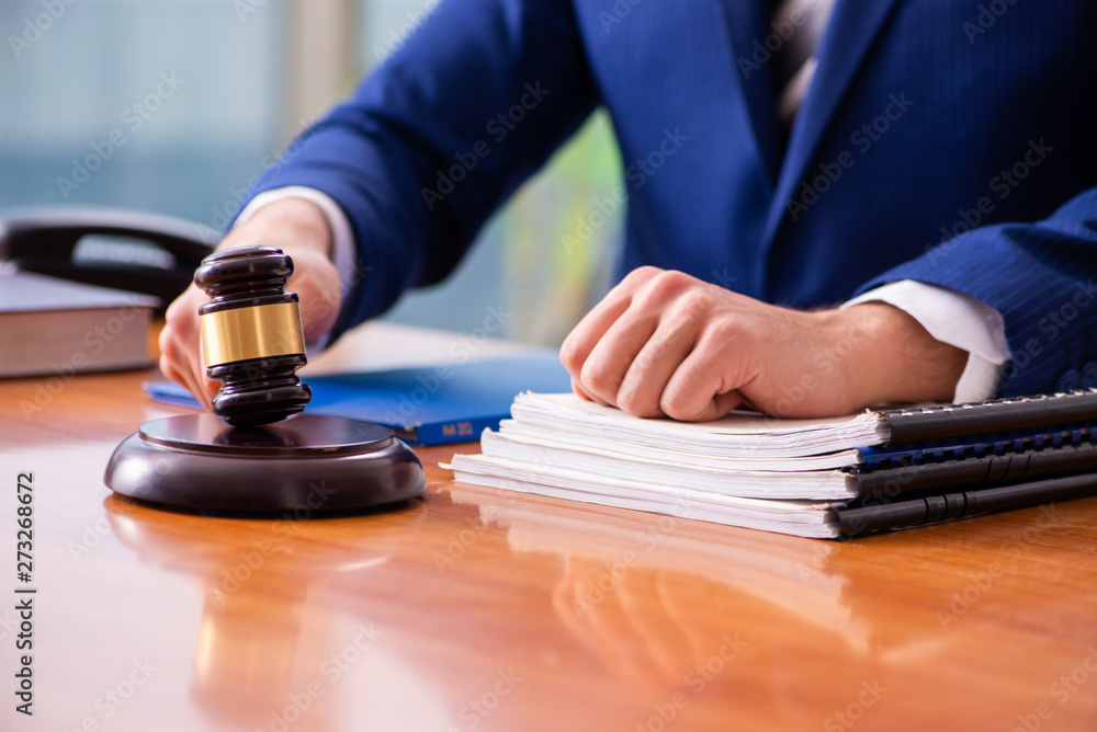 Young male judge sitting in courtroom Young male judge sitting in courtroom