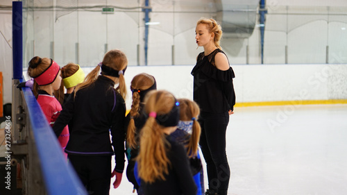 Female coach in figure skating talk to girls at indoor rink