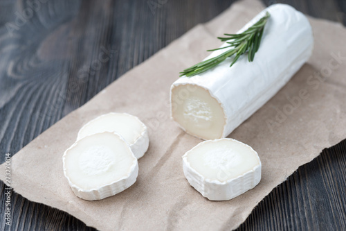 Fresh goat cheese with slices on paper.