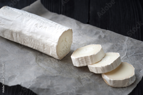 Fresh goat cheese with slices on paper.