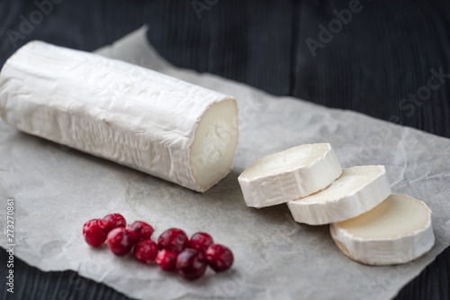 Fresh goat cheese with red berries slices on paper.