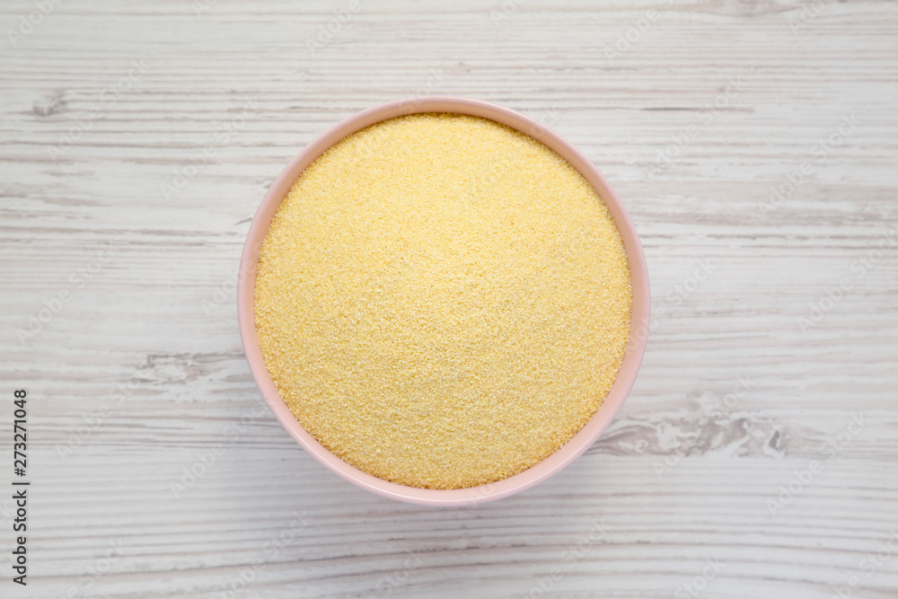 Dry semolina durum flour in a pink bowl over white wooden background, top view. Overhead, from above, flat lay. Dry semolina durum flour in a pink bowl over white wooden background, top view. Overhead, from above, flat lay.