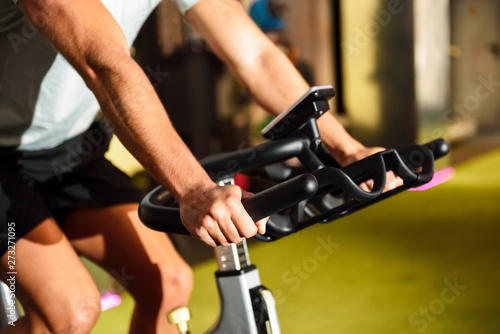 Hands of a man training at a gym doing cyclo indoor.