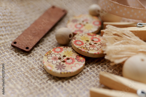 Close-up: Wooden buttons with floral print and other details for needlework lie on the burlap