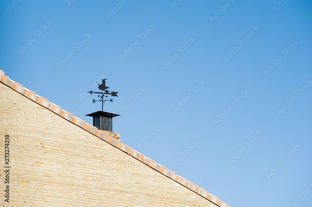 weather vane in the shape of a witch, on the roof