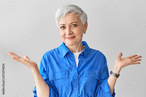 I have no idea. Stylish emotional middle aged mature female with short gray hair expressing confusion, shrugging her shoulders, being perplexed and at loss, saying I don’t know. Body language photo