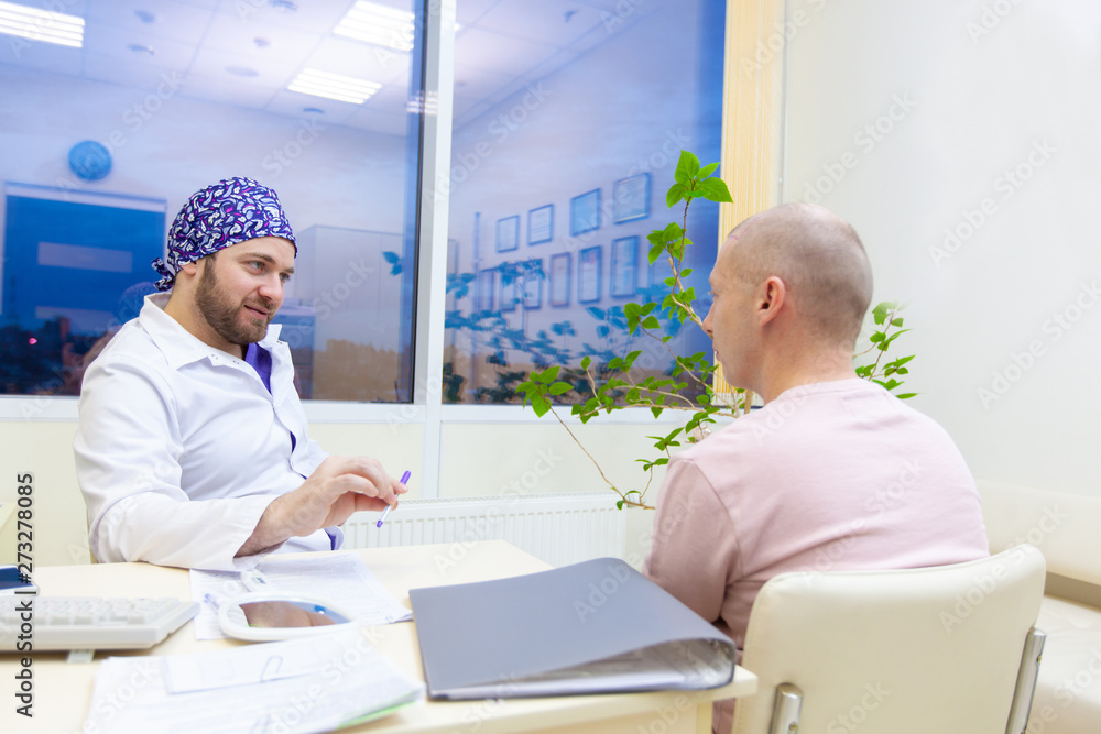 Baldness treatment. Patient suffering from hair loss in consultation with a doctor. Preparation for hair transplant surgery. The line marking the growth of hair. The patient controls the marking in Baldness treatment. Patient suffering from hair loss in consultation with a doctor. Preparation for hair transplant surgery. The line marking the growth of hair. The patient controls the marking in