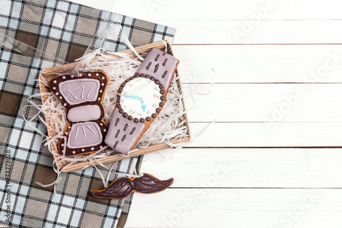 Box of delicious creative cookies with copy space on checkered napkin on white wooden table. Happy Father's Day concept.