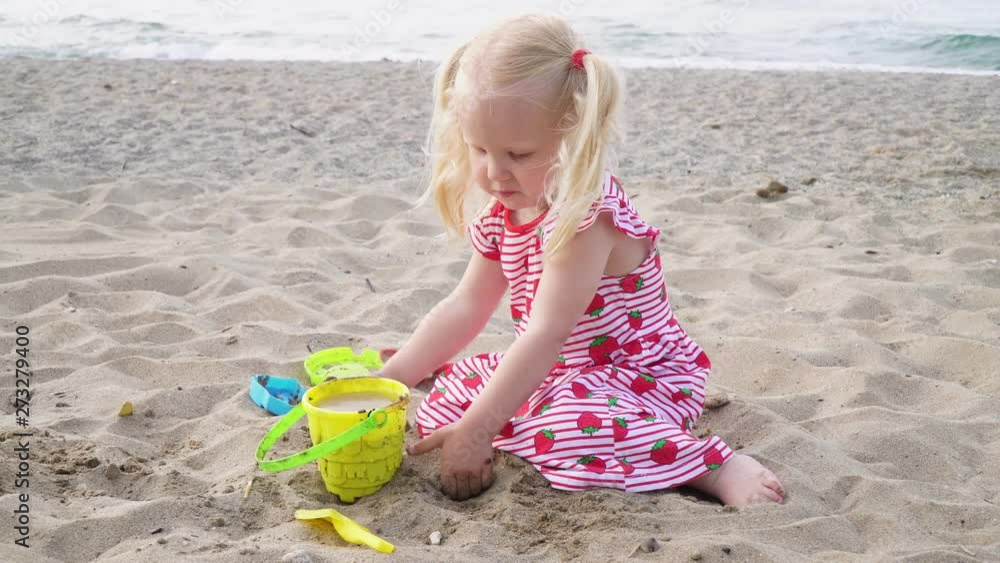 Child girl blonde plays on the sandy beach of the sea. Child girl blonde plays on the sandy beach of the sea.