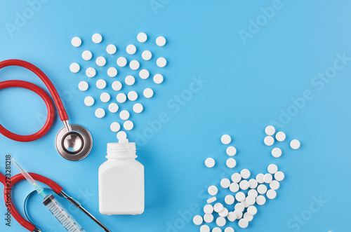 Pills tablets capsules closeup. On a blue background, a jar of medicine. On a blue background, a jar of medicine and a stethoscope.