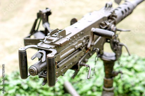 Closeup and back view of M2 .50cal Browning machine gun with tripod standing in bunker and on blurry background. photo