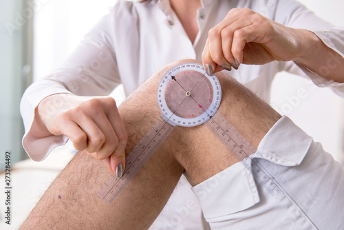 Quadro su tela Female doctor checking patient's joint flexibility with goniometer