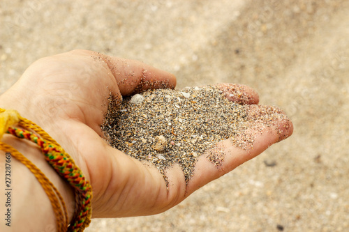 Sand from small crushed shells in a   womans hand. photo