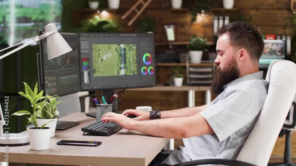 Video editor working in professional software. He uses a dual screen setup and works in modern designed studio office Video editor working in professional software. He uses a dual screen setup and works in modern designed studio office